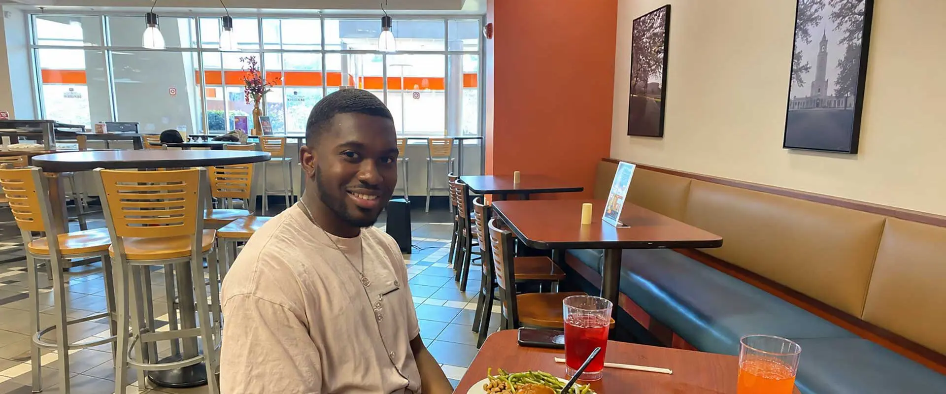 Student smiling while sitting at table with food and beverages