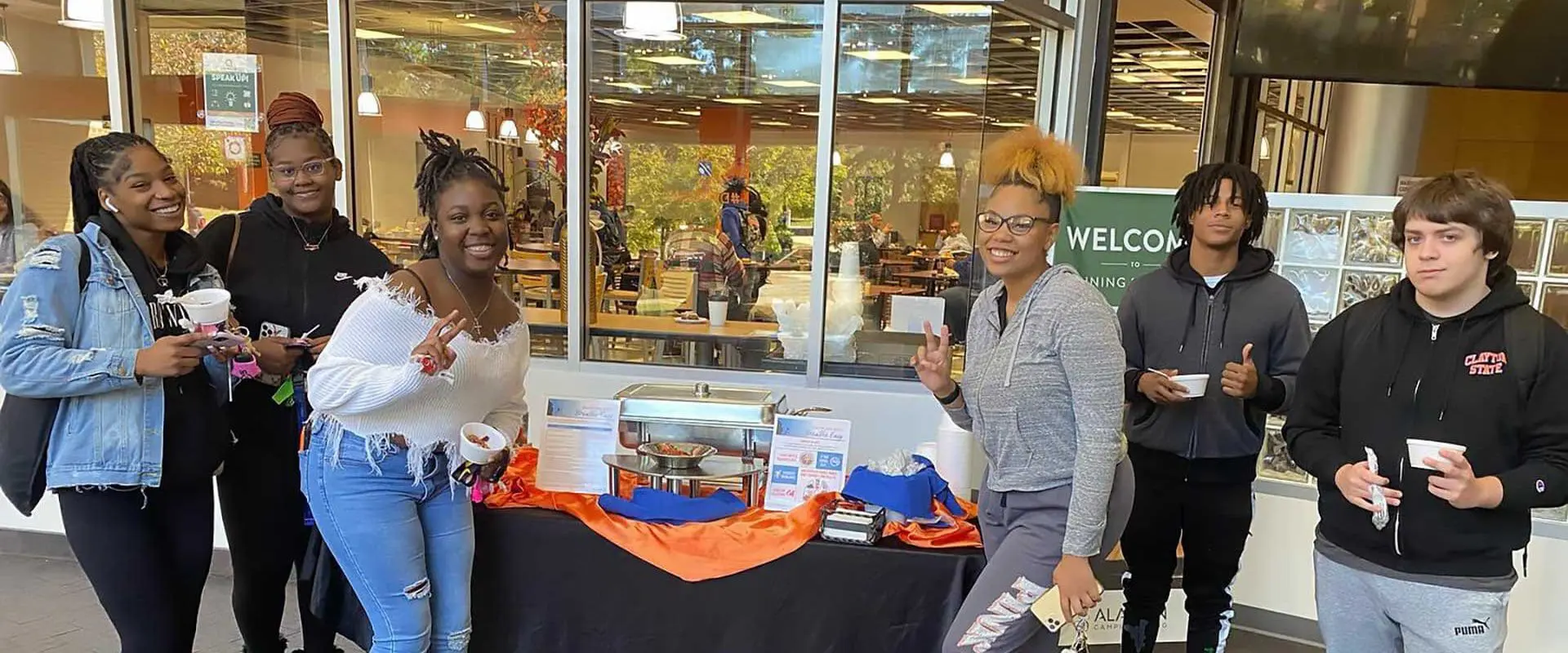 Students smiling outside Lakeside Dining Hall at event table
